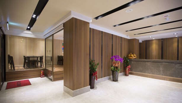En moderne lobby med en receptionsdisk, et siddeområde og en brandslukker på gulvet.