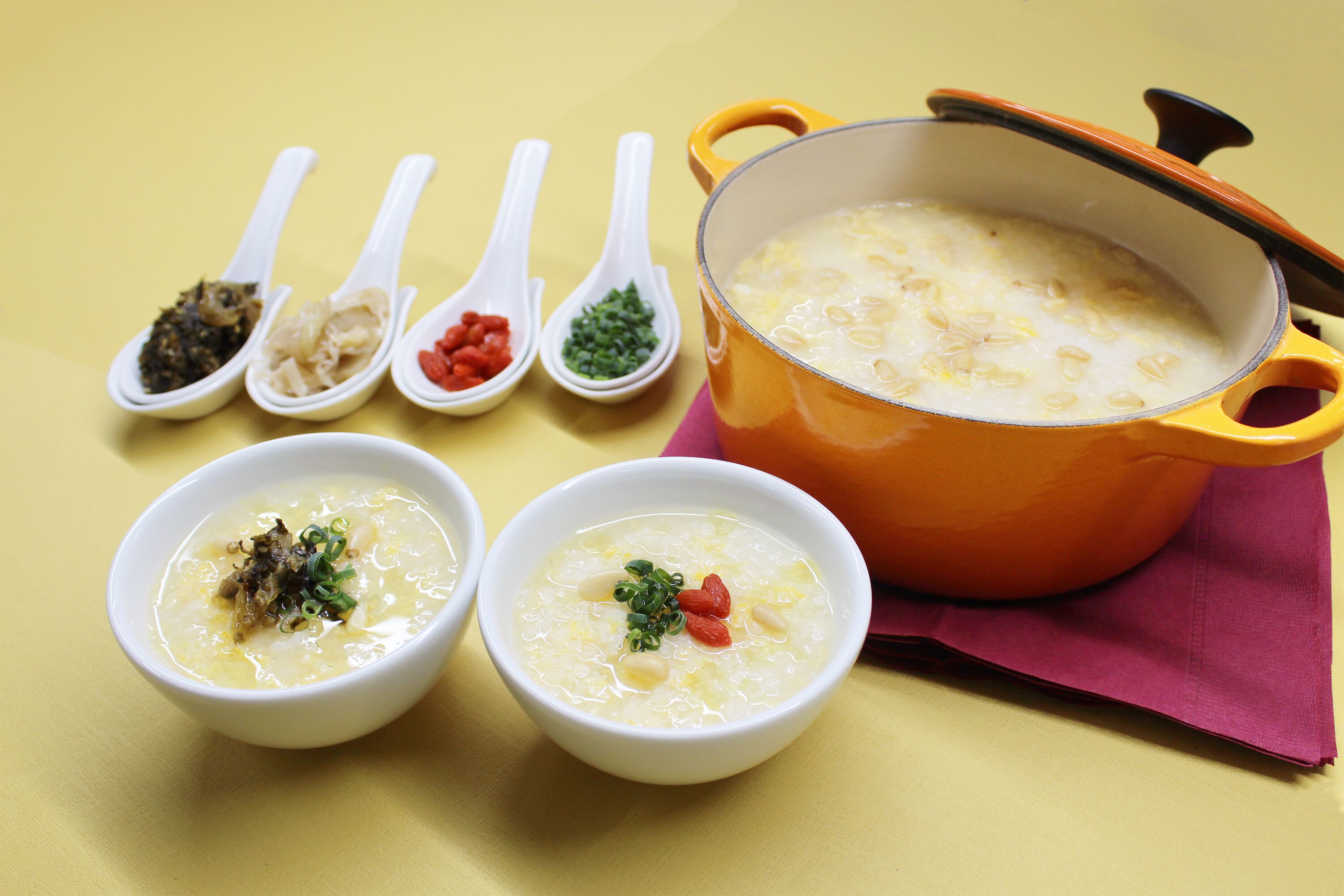 Uma panela de sopa com duas tigelas à frente, cada uma com guarnições diferentes.