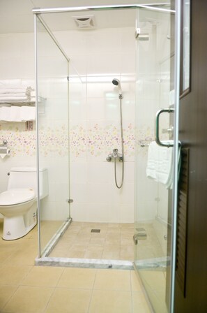 A glass-enclosed shower with a handheld showerhead and a wall-mounted faucet. - Apple Tree B&B (Hualien City)