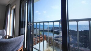 A balcony with a view of the sea and rocky coastline. - Jeju Amoje (Seogwipo)