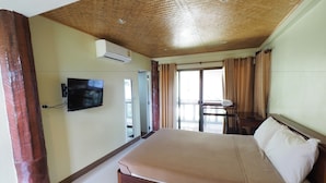 A bedroom with a large bed, a television mounted on the wall, and a window with curtains. - Banyang Resort (Kanchanaburi)