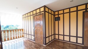 A room with a wooden floor, a decorative door, and a view of greenery outside. - Banyang Resort (Kanchanaburi)