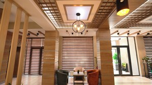 A modern lobby with a reception desk, seating area, and a ceiling with a skylight and pendant lighting. - Sayyoh Hotel (Tashkent)