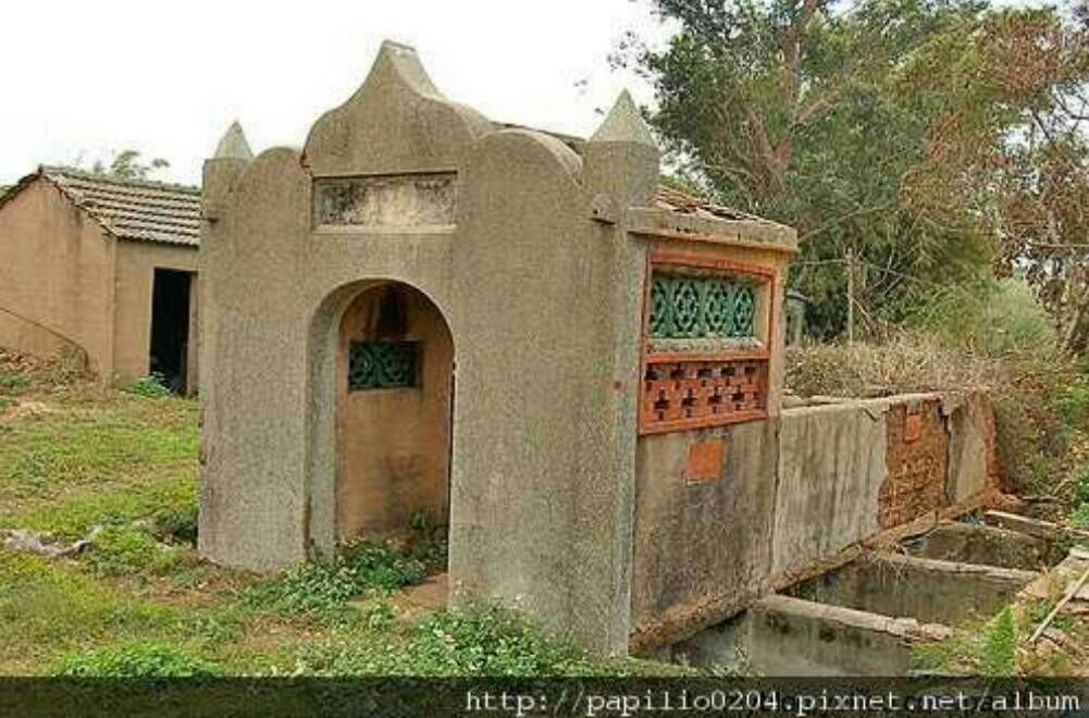 A small, rustic building with a simple archway entrance and a small window.