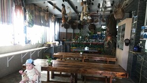 A rustic interior with wooden tables and benches, a small child seated, and various hanging decorations. - tai-chia Bed and Breakfast (Jincheng)