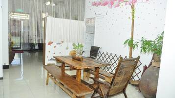A dining area with a wooden table and benches, a decorative wall with a floral mural, and a large potted plant.
