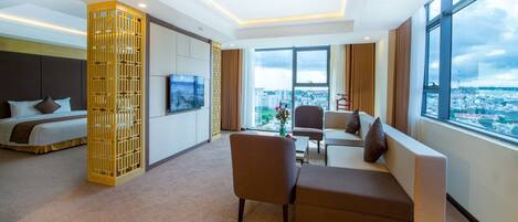 A hotel room with a bed, a sofa, a TV, and a large window with a city view.