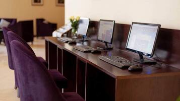 A reception desk with multiple computer stations, a purple chair, and a vase with flowers.