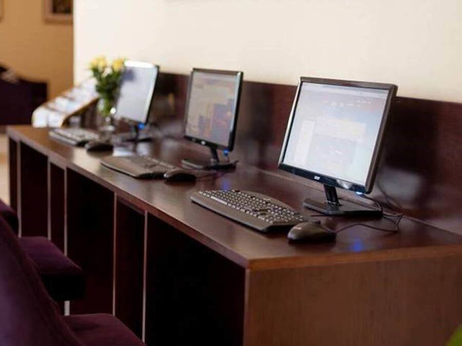 A reception desk with multiple computer stations, a purple chair, and a vase with flowers.