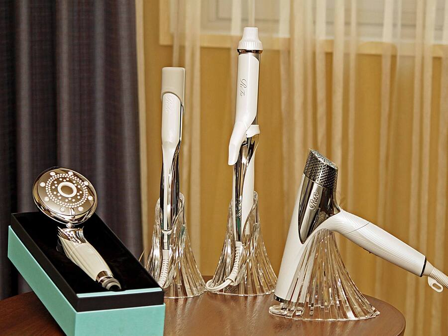 A collection of silver hair styling tools displayed on a wooden table with a teal box in the background.