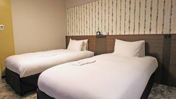 A hotel room with two single beds, a headboard with a clock, and a striped wallpaper on the wall.