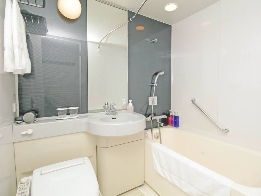 A modern bathroom with a sink, mirror, and bathtub.