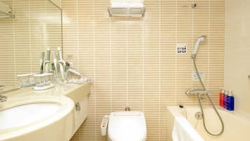 Un baño con lavamanos, inodoro y bañera, equipado con cabezal de ducha y dispensadores de jabón para manos.