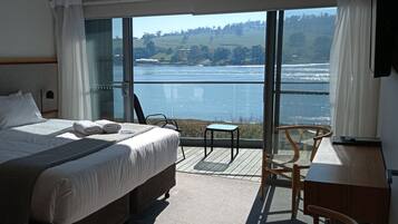 Habitación de hotel con una cama grande, una mesita, una silla y vistas a un lago.