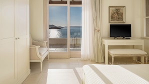 A bedroom with a bed, a TV, a chair, a desk, and a view of the sea. - Sk Place Crete Luxury Seafront Villas (Apokoronas)