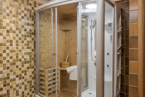 Un espace de douche clos par des parois de verre, avec un intérieur en bois, un mur carrelé et une serviette blanche accrochée à la porte.