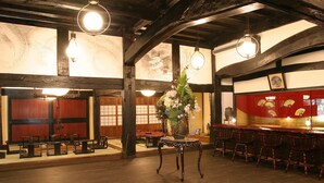 A traditional Japanese-style interior with wooden beams, tatami flooring, and a bar area with wooden chairs.