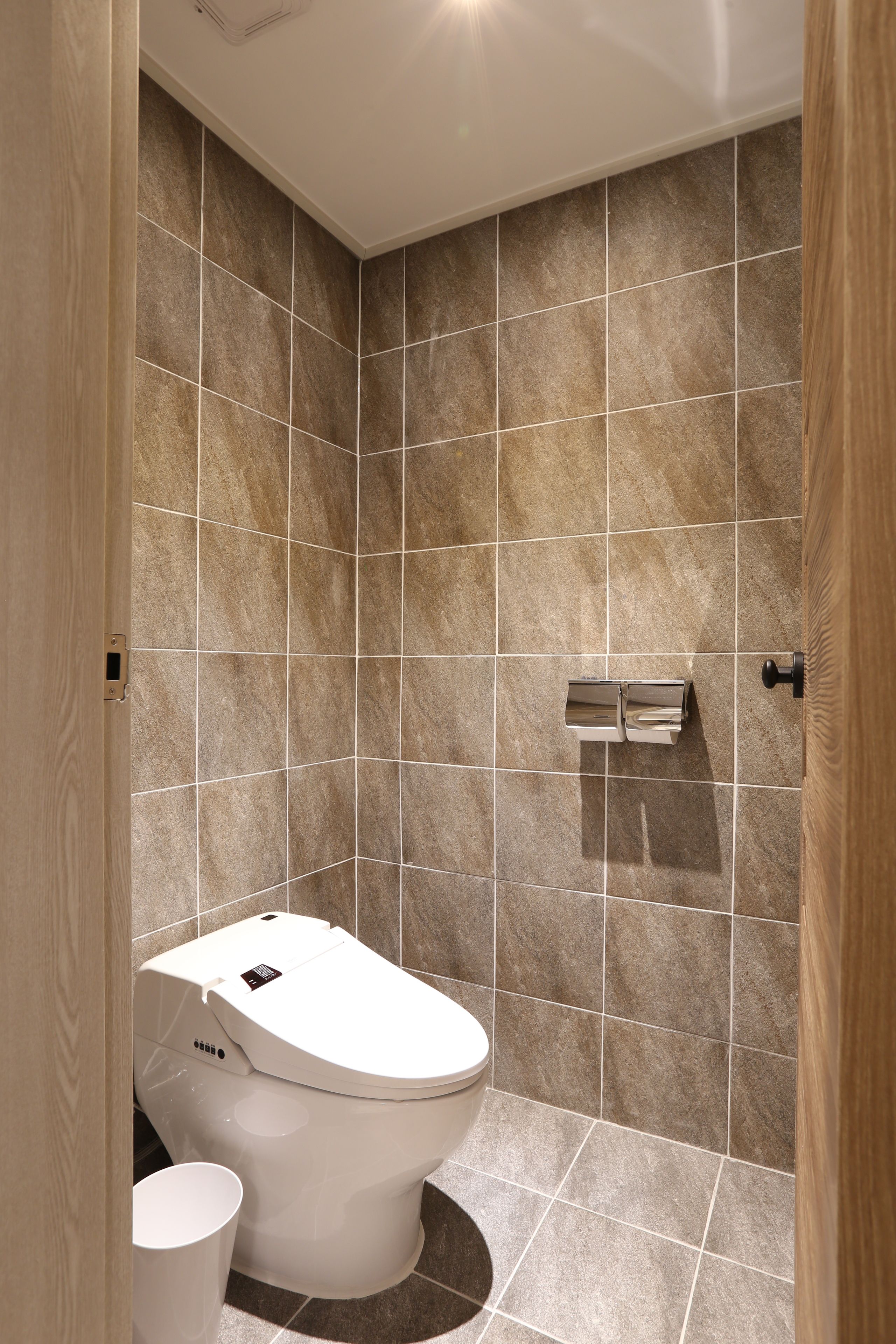 A modern bathroom with a toilet, bidet, and a trash bin.