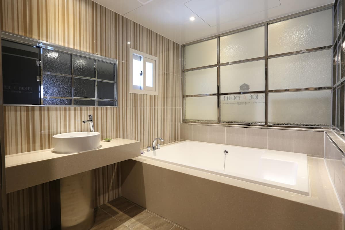 Un baño moderno con una bañera grande, un tocador con lavamanos y un ventanal con paneles de vidrio esmerilado.
