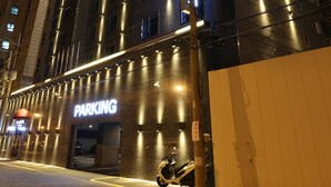 Un bâtiment moderne avec une enseigne lumineuse indiquant « PARKING » et une entrée bien visible.