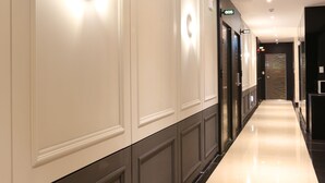 Un long couloir bien éclairé, doté d’un plancher ciré, qui mène à une porte portant l’inscription « GOS ».