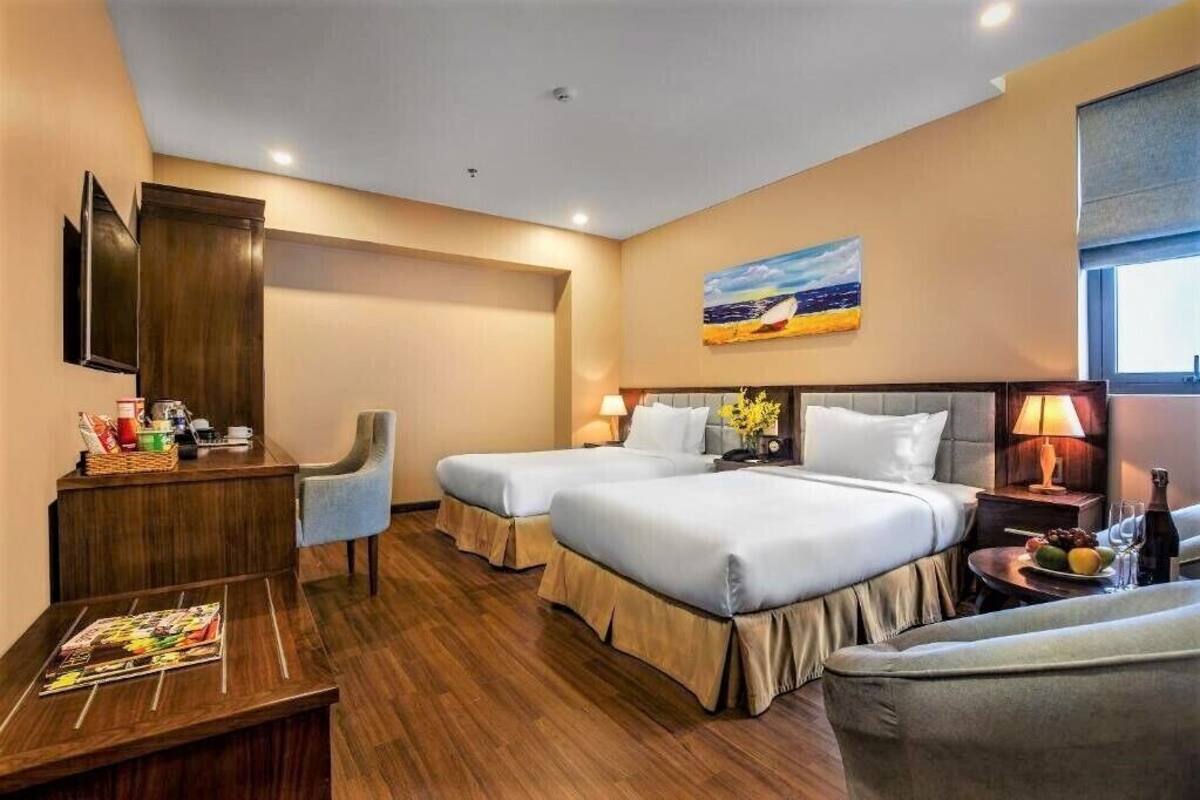 A hotel room with two beds, a desk, a chair, a TV, and a painting on the wall.
