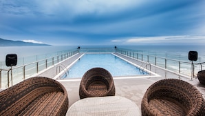 A poolside area with wicker chairs and a pool overlooking the ocean. - Yarra Ocean Suites Danang (Da Nang)