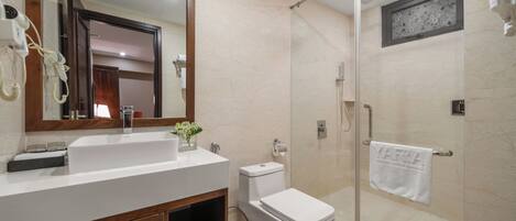 A bathroom with a white sink, mirror, toilet, and shower.