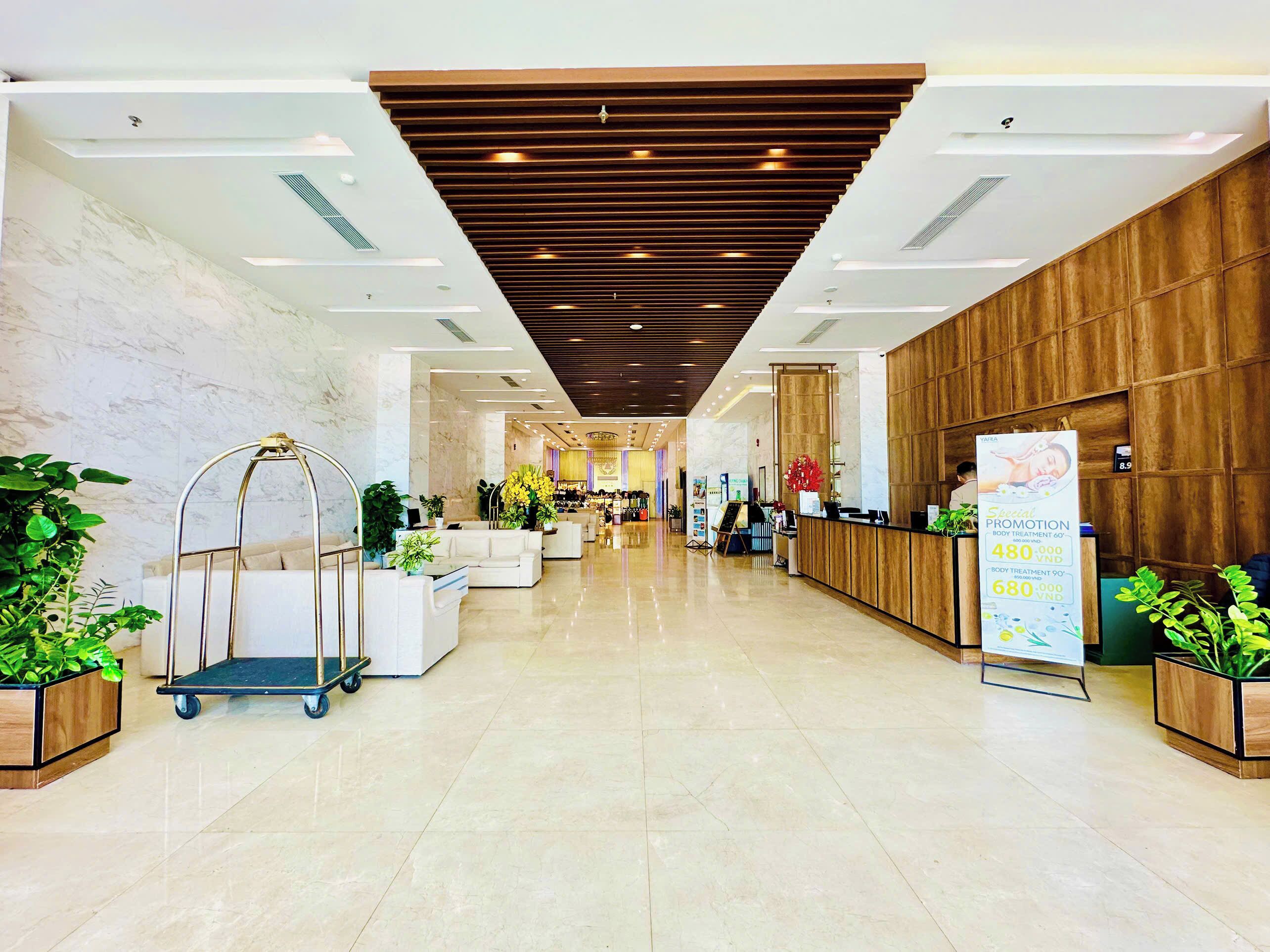 A hotel lobby with a reception desk, seating area, and a view into the restaurant.