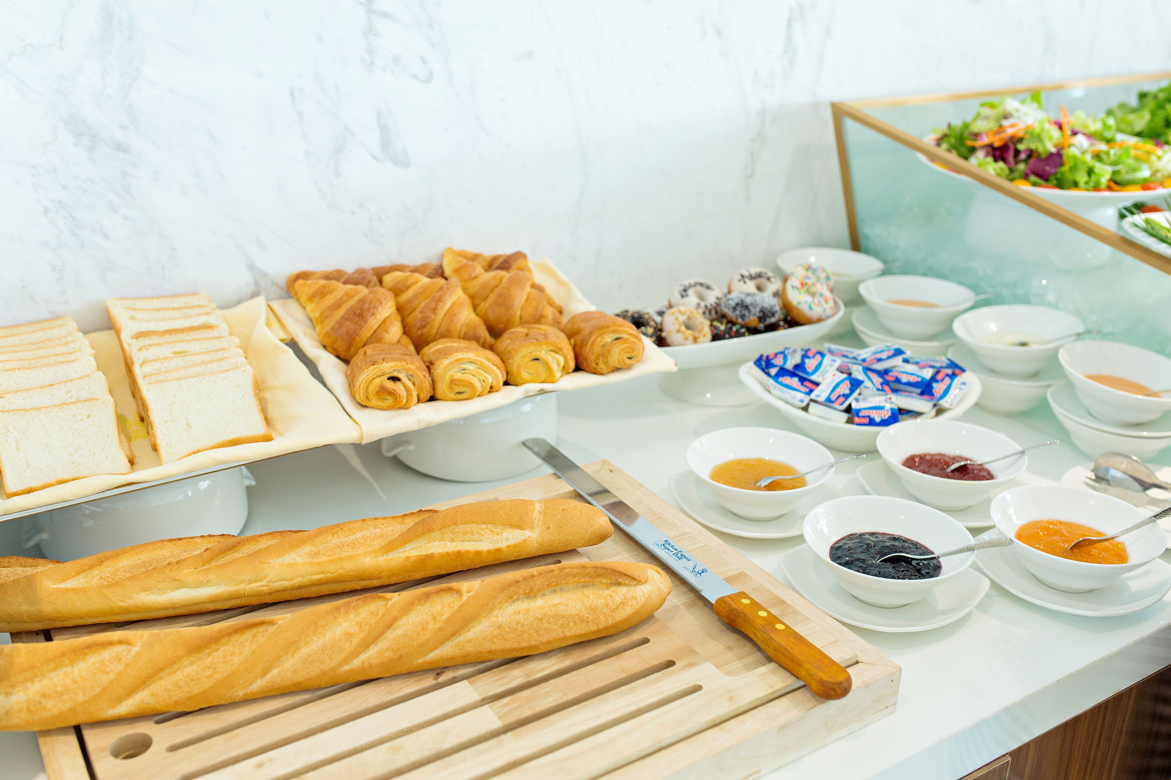 Ein Buffet mit Brot, Gebäck und verschiedenen Beilagen.