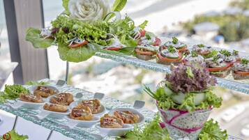 Une table de buffet garnie de divers plats et agrémentée d’une composition florale décorative.