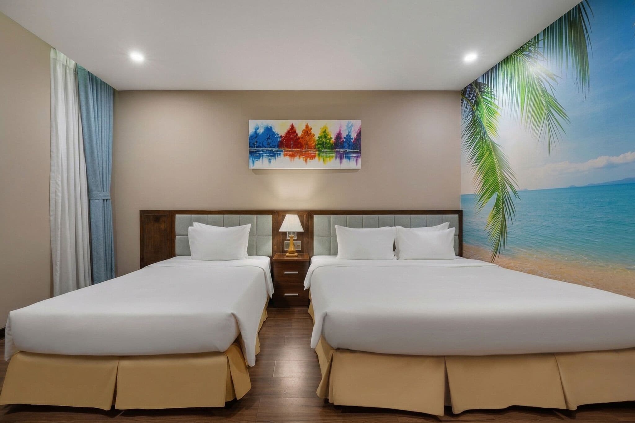 Ein Hotelzimmer mit zwei Betten, einem Gemälde, einer Lampe und einem Wandbild mit Strandmotiv.
