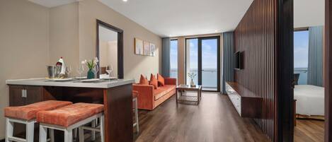 A modern living space with a kitchen area, a sofa, a dining area, and a large window offering a view.