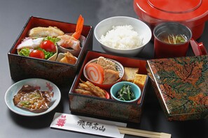 Un repas japonais traditionnel composé de différents plats présentés dans des récipients séparés, notamment du riz, du poisson et des légumes.