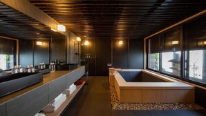 Une salle de bain moderne avec une baignoire en bois, un grand miroir et un plan de toilette avec des articles de toilette.