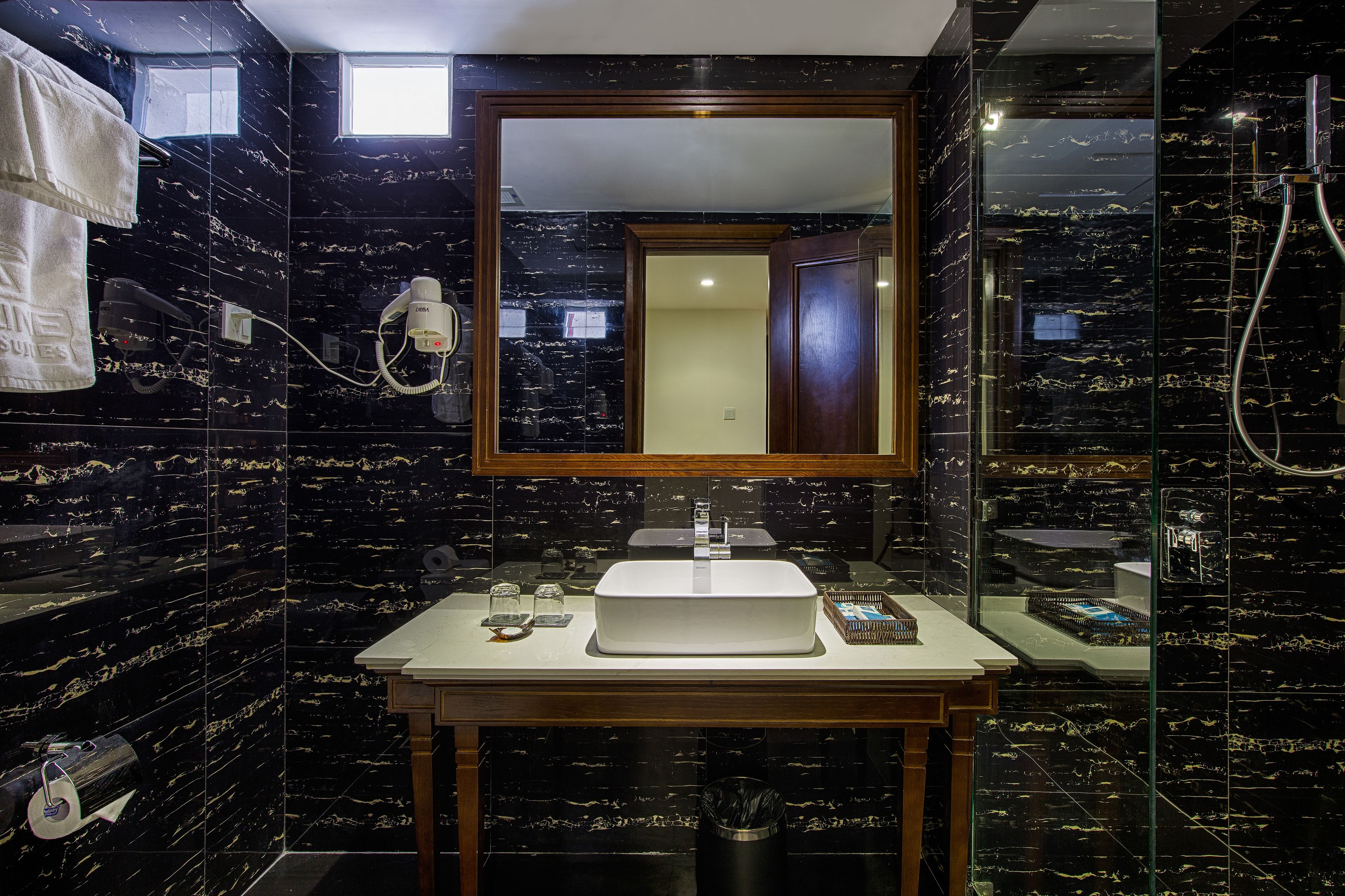 A bathroom with a large mirror, a sink, and a shower area.