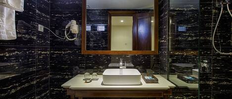 A bathroom with a large mirror, a sink, and a shower area.