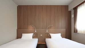A hotel room with two single beds, a wooden headboard, bedside tables, and a window with curtains. - Smile Hotel Hakata Ekimae (Fukuoka)