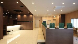 A modern reception area with a wooden reception desk, a bench, and a waiting area with a glass partition. - Smile Hotel Hakata Ekimae (Fukuoka)