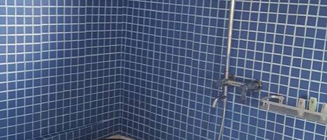 A bathroom with a bathtub, a shower, and blue tiled walls.