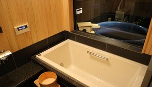 Un baño moderno con una bañera grande, un tocador de madera y un espejo que refleja la bañera azul.