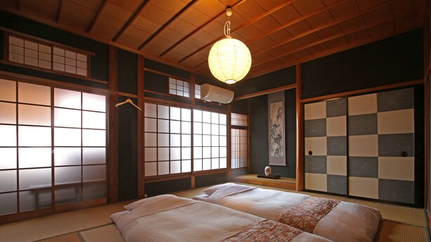Una habitación japonesa tradicional con suelo de tatami, paneles shoji y un farolillo de papel colgante.