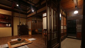 Una habitación tradicional japonesa con esteras de tatami, una mesa de madera baja con una tetera y puertas correderas.