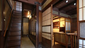 Un interior japonés tradicional con una escalera de madera, puertas correderas y una pequeña zona de estar.