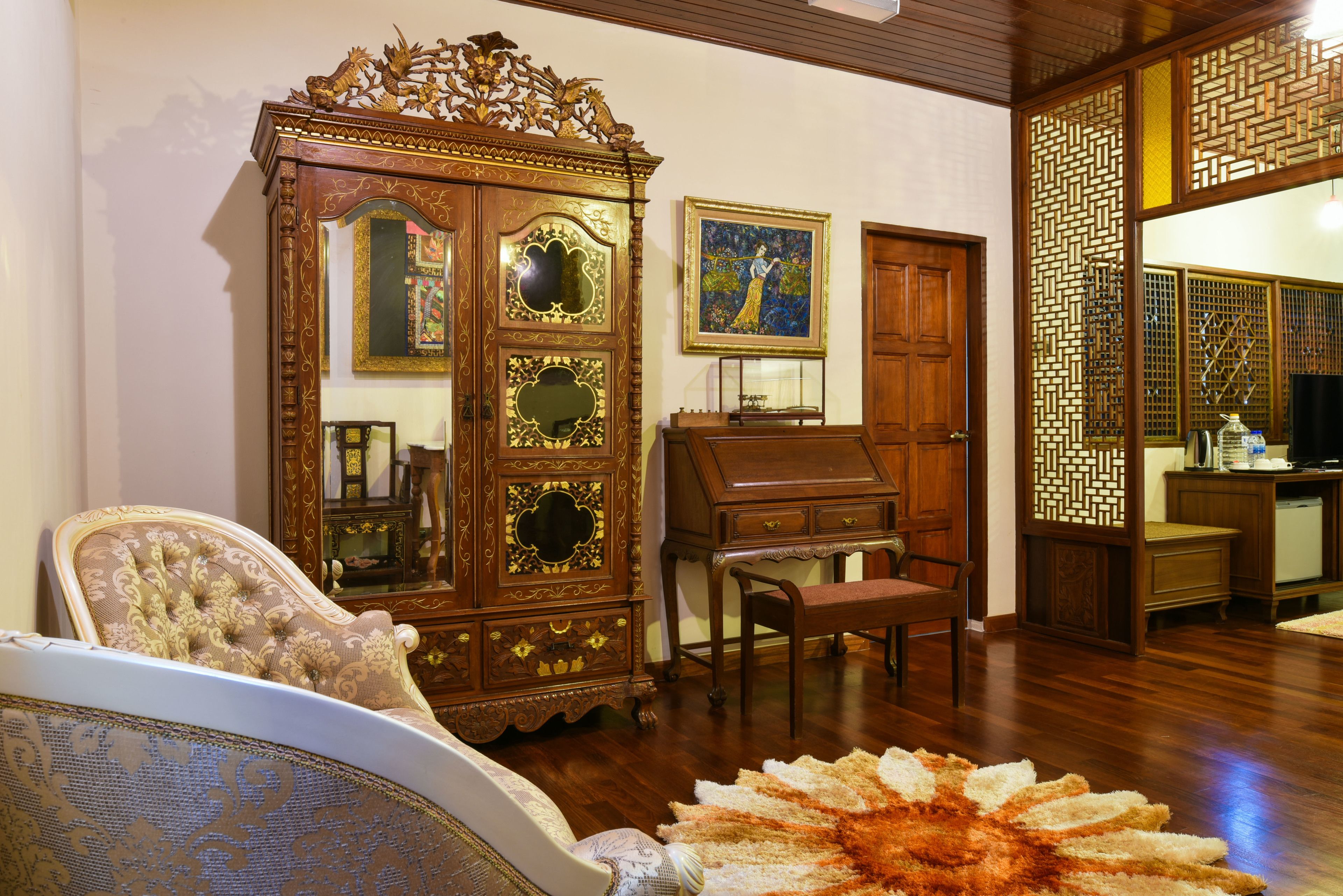Una habitación tradicional con un aparador de madera, una silla, un escritorio y un biombo decorativo.