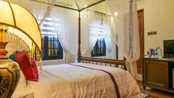 A four-poster bed with a canopy, a large vase, and a red pillow.