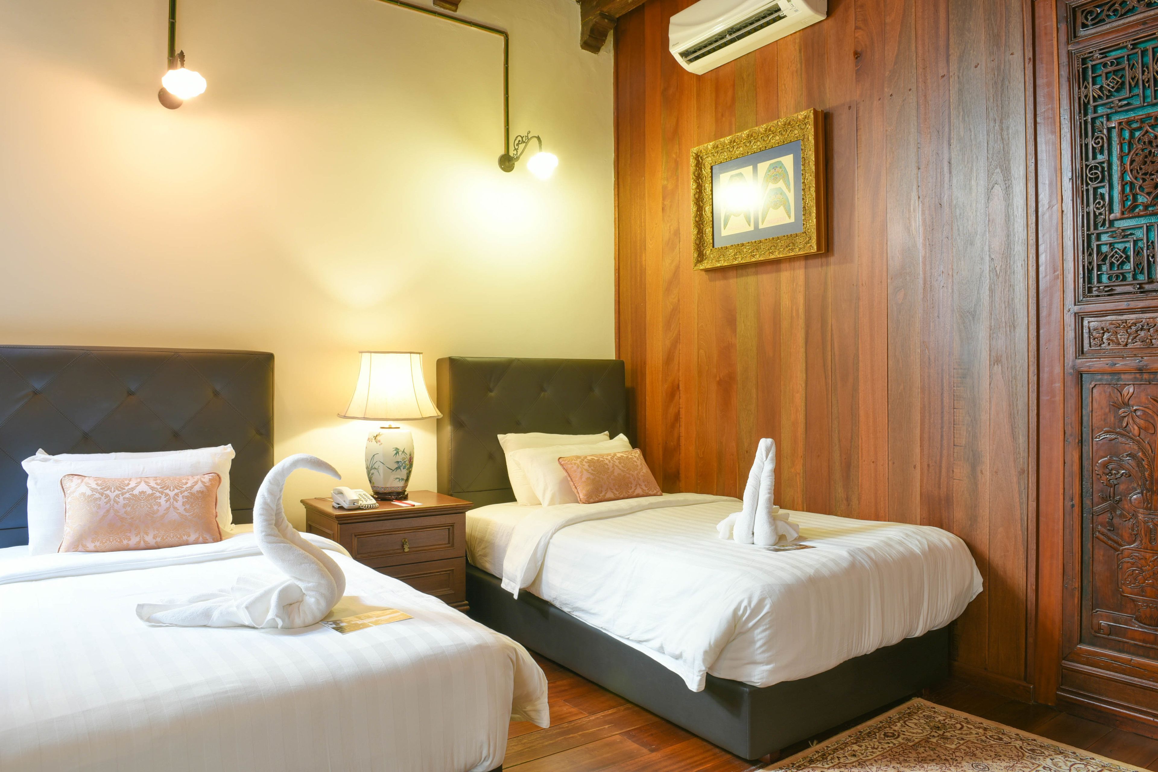 A hotel room with two beds, a nightstand, a lamp, and a decorative wall panel.