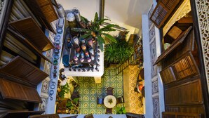 A narrow, ornate hallway with patterned walls, wooden shutters, and a variety of decorative items including plants and pottery. - 5 Heeren (Malacca City)