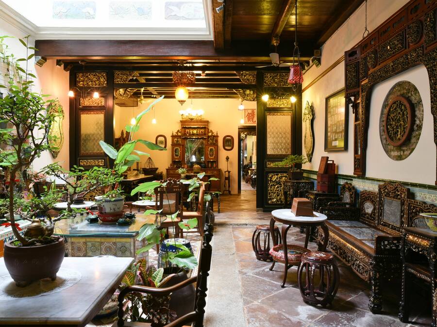 Un intérieur doté d’un plafond en bois, de meubles richement décorés et d’une variété de plantes en pot.