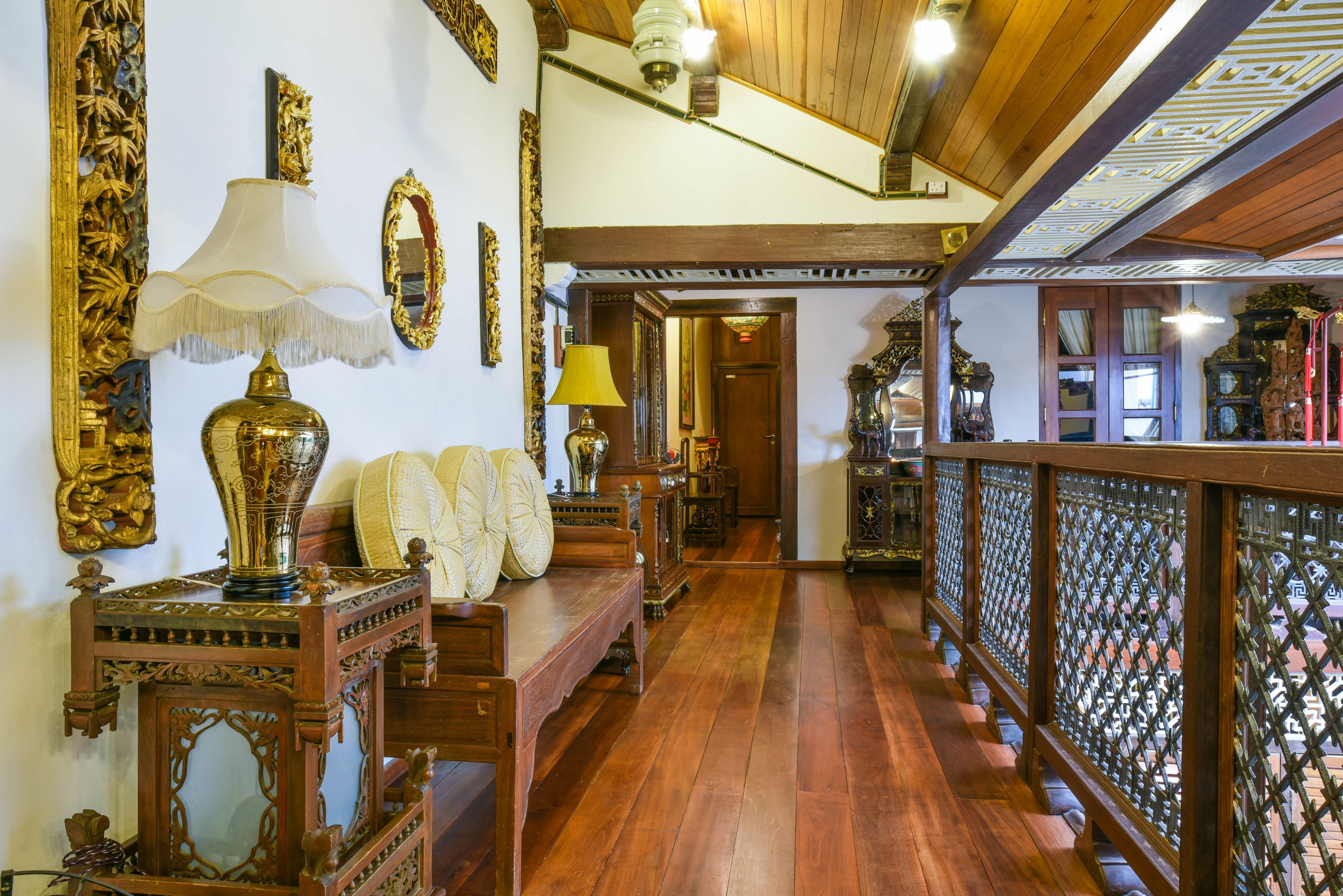 Un pasillo con suelo de madera, muebles ornamentados y espejos decorativos.